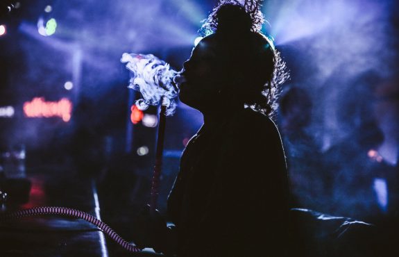 Young lady smoking hookah shisha pipe in a busy cafe