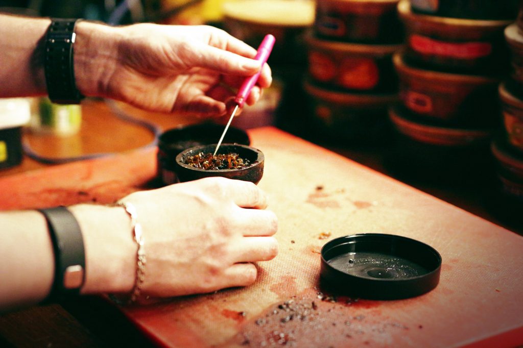 Hands of somebody loading tobacco bowl for shisha smoking