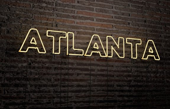Brick wall with neon light that says Atlanta.
