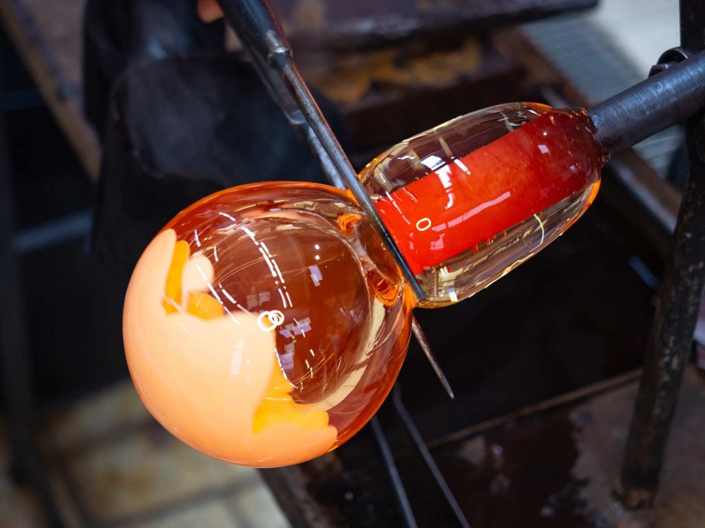 Glass blowing a bottle in a hot shop.